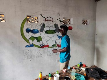 Egy tanuló épp a klub logóját festi a terem falára