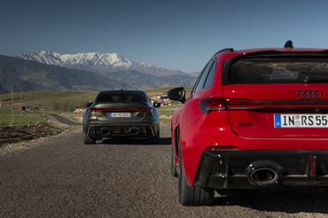 The Audi RS 5 Sedan in Bedford green and the Audi RS 5 Avant in Progressiv red on an open country road framed by the Atlas Mountains.
