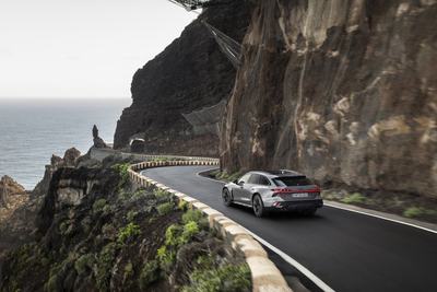 Three-quarter rear view of Audi A6 allroad (pearl grey) on a winding coastal road (dynamic shot)