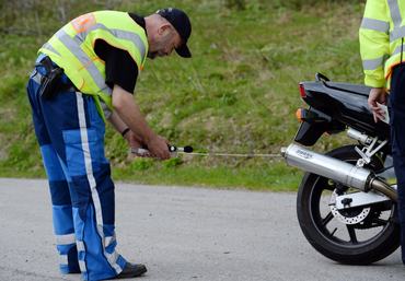 A policeman checks the noise level coming from a motorcycle exhaust on the Feldberg in the Black Forest, Germany, 18 May 2014. After a marked increase in deadly motorcycle accidents, the police in Freiburg have increased controls on motorcycles. Photo: Patrick Seeger/dpa | usage worldwide (Photo by Patrick Seeger/picture alliance via Getty Images)