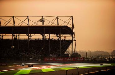 Brazilian Scuderia Ferrari Formula One team racing driver Felipe Massa driving his F138 racing car around Turn One of the circuit ahead of Finnish Williams racing driver Valtteri Bottas in his FW35 car while being watched by hundreds of fans and spectators sitting and standing in the start and finish straight Turn One grandstand,  alongside Airtel advertising signs and hoardings during the 2013 Indian Grand Prix, Buddh International Circuit, Greater Noida, India, on the 27th October 2013. (Photo by Darren Heath/Getty Images), (Editor's Note: Image has been digitally enhanced.)