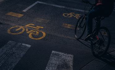 Unrecognisable person riding his bicycle along a cycle lane. In the picture we can see several drawings of a bicycle, painted on the road to indicate a bicycle lane. Image taken in the city of Budapest.