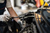 Mechanic working on an engine using a wrench, showcasing concepts of automotive repair and maintenance.