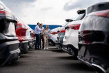 Happy Latin American car salesperson showing cars to a couple shopping at the dealership