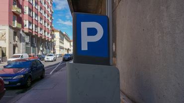 Budapest, Hungary 08-03-2025. Blue parking sign stands on a city street. Residential buildings and parked cars in the background. Urban planning, parking tariffs, limited parking space.