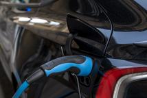 Close-Up Of Electric Vehicle Charging Plug Connected To Urban EV Charger Station With Blue Cable