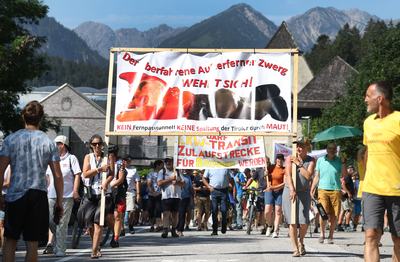 27 June 2026, Austria, Reutte: Protesters holding a sign that reads, "The run-over Außerfern dwarf is fighting backno Fern Pass tunnel, no division of the Tyroleans through tolls!" are gathering near the closed B179 Fern Pass Road to form a protest march and hold a rally. Photo: Karl-Josef Hildenbrand/dpa (Photo by Karl-Josef Hildenbrand/picture alliance via Getty Images)
