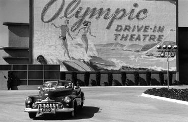 28th April 1951: A couple in an open-top car driving past a sign advertising Hollywood's Olympic drive-in theatre in Los Angeles, California. Original Publication: Picture Post - 5298 - Two Men In Hollywood - pub. 1951 (Photo by Kurt Hutton/Picture Post/Hulton Archive/Getty Images)