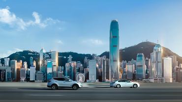 Traffic on street against Hong Kong cityscape with clear blue sky